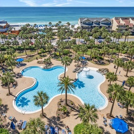 Stunning aerial view of the resort's expansive pool complex with tropical palms, just steps from pristine beach access.