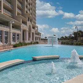 Elegant pool area with sparkling fountains and comfortable lounging spaces at this beachfront high-rise property.
