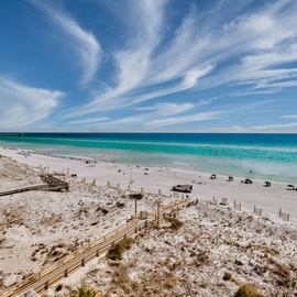 Pristine white sand beach with emerald waters and dramatic cloud formations stretching along the coastline.