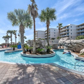 Tropical Waterscape Resort swimming pool with decorative rock features, lazy river, and palm trees under sunny Florida skies.