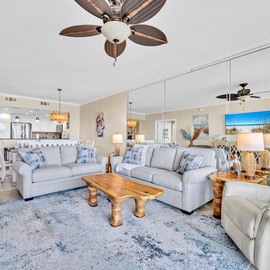 Relax in your spacious coastal living room with plush sectional seating, warm wood accents, and beachy decor that invites you to unwind in comfort.