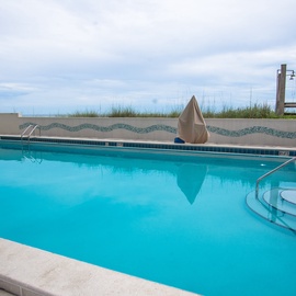 Sparkling blue Sundestin community pool with mosaic tile accents invites you to take a refreshing dip under open skies.