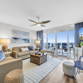 Unwind in your bright, coastal living room with ocean views framing the balcony. Sink into plush seating, enjoy the ceiling fan's breeze, and catch your favorite shows on the flat-screen TV.