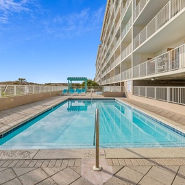 Beachfront property featuring a swimming pool with balcony accommodations under clear blue skies.