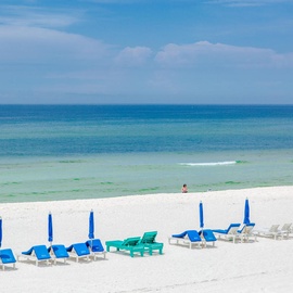 Pristine white sand beach with crystal-clear emerald waters stretching to the horizon under brilliant blue skies.