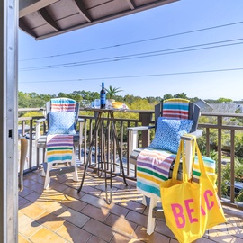 Step onto your private balcony where colorful striped towels and a cheerful beach bag await your seaside adventures.