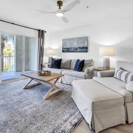 Relax in your spacious living room featuring plush sectional seating and a coastal vibe, with tropical views just beyond your private balcony.