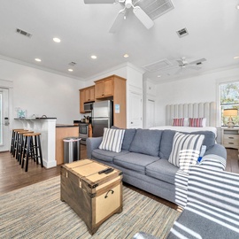 Relax in your bright open-plan living space where coastal comfort meets modern convenience, with plush seating and fully equipped kitchen.