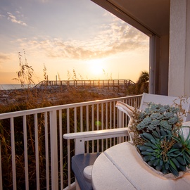 Stunning beachfront balcony offering panoramic gulf views and golden sunset vistas through natural coastal dunes.