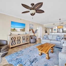 Relax in your coastal-themed living room with plush seating, tropical ceiling fan, and beach artwork creating the perfect vacation atmosphere.