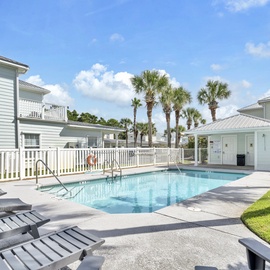 A sparkling community pool surrounded by tropical palms creates the perfect backdrop for relaxation at this charming resort-style property.