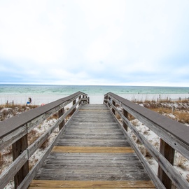 Wooden boardwalk leads directly to pristine sandy beach and emerald Gulf waters, providing easy access to coastal adventures.