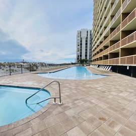 Expansive pool deck featuring two pristine pools with waterfront views and modern high-rise accommodations.