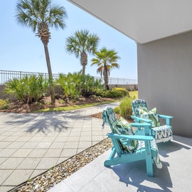 Unwind on your private patio with turquoise chairs overlooking tropical palms and landscaped gardens—your perfect coastal escape awaits.