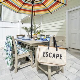 Your private patio beckons with colorful umbrella shade, perfect for morning coffee or evening meals under the open sky.