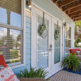 Your private porch retreat awaits with comfortable seating and tropical decor, perfect for morning coffee or evening relaxation.