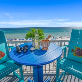 Sip your morning coffee on this oceanfront balcony, where vibrant turquoise chairs and stunning sea views create the perfect coastal retreat.