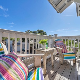 Relax on your sunny private balcony with colorful striped cushions and rustic wooden furniture, perfect for morning coffee.