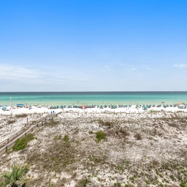 Pristine white sand beach stretches along turquoise waters under endless blue skies, with boardwalk access to this stunning coastal destination.