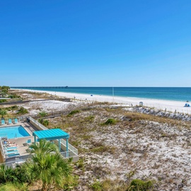 Spectacular beachfront view showcases pristine white sand, turquoise waters, and the property's inviting pool area below.