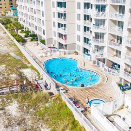 Aerial view of the Island Princess resort with a swimming pool, hot tub, and direct beach access through sandy dunes and boardwalk pathways.