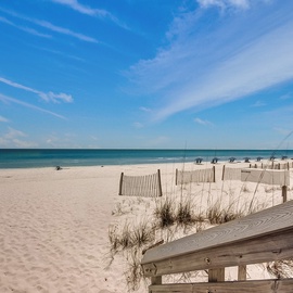 Pristine white sand beach with turquoise waters stretches endlessly under brilliant blue skies, creating the perfect coastal escape.