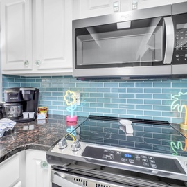 Cook your favorite meals in this fully-equipped kitchen featuring modern appliances and beautiful turquoise tile backsplash.