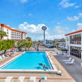 Bright blue swimming pool surrounded by comfortable loungers and tropical landscaping, with the distinctive water tower as a local landmark.