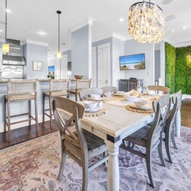 Gather around your stylish dining table beneath the sparkling chandelier, where every meal becomes a celebration in this elegant open space.