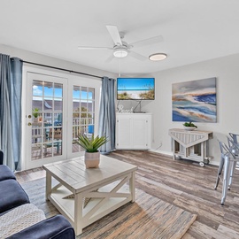 Welcome to Summer Breeze B306 - Another Day in Paradise - our bright, coastal-themed living space with beach artwork, comfy seating, and French doors opening to your private balcony.
