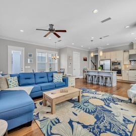 Relax in your spacious open-plan living area where coastal blue sofas and tropical patterns create the perfect beach house vibe.