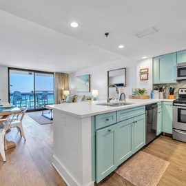 Your bright, modern kitchen flows seamlessly into the living space, where turquoise cabinets and stainless appliances await your culinary adventures.