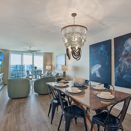 Gather around this elegant dining table beneath a stunning chandelier, where ocean-inspired artwork creates the perfect backdrop for memorable meals.