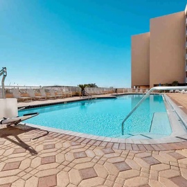 Take a refreshing dip in the sparkling pool, complete with accessibility features and poolside lounging area under sunny skies.