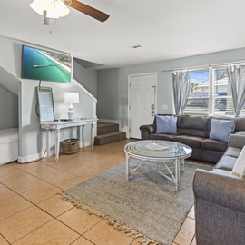Unwind in your bright, coastal living room with plush seating, entertainment center, and serene ocean artwork to set your vacation mood.