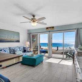 Unwind in your coastal living room where ocean waves meet comfortable seating and stunning sea views through sliding glass doors.
