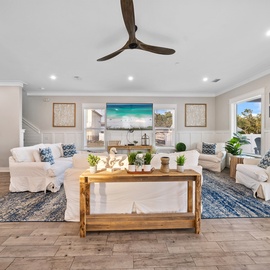 Relax in your spacious living room featuring plush white sofas, coastal-inspired decor, and warm wood accents that create the perfect gathering space.