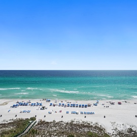 Pristine Gulf Coast beach with emerald waters and white sand stretches along the shoreline under brilliant blue skies.