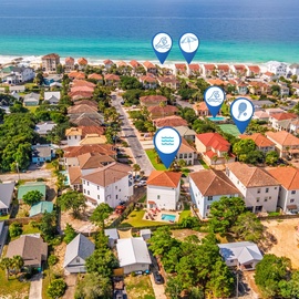 Aerial view of a beachside community with emerald waters and sandy shores, showcasing the neighborhood and proximity to the coast.