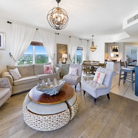 Relax in your elegantly appointed living space featuring coastal charm, plush seating, and stunning windows that frame beautiful city views.