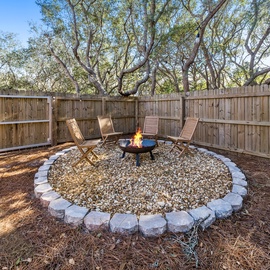 Gather around your private fire pit surrounded by comfortable chairs, perfect for evening conversations under the stars in this peaceful backyard retreat.