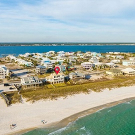 Stunning aerial view of coastal community with pristine beach and emerald Gulf waters stretching endlessly.