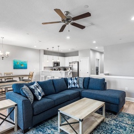 Relax in your spacious open-plan living space, where coastal blue sofas and modern amenities create the perfect home base for your getaway.