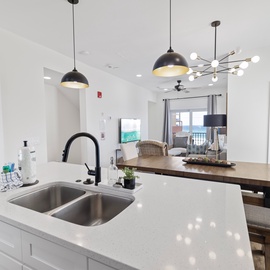 Step into your bright, modern kitchen with sleek countertops and stylish pendant lighting, flowing seamlessly into the dining and living areas where you can relax and enjoy ocean glimpses through the windows.