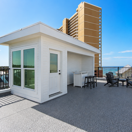 Expansive rooftop terrace features modern cabin structure with panoramic ocean views and comfortable outdoor seating area.