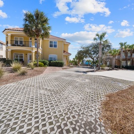 Mediterranean-style vacation homes feature colorful facades and tile roofs, set among palm trees with convenient paved parking areas.