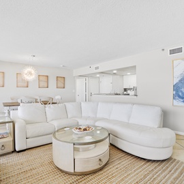 Sink into plush white sectional seating in this bright, open-plan living space where coastal artwork and natural textures create your perfect retreat.