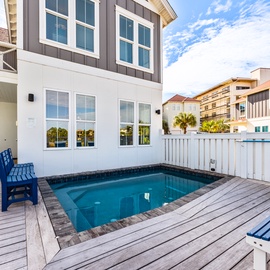 Your private pool deck beckons with blue lounge chairs and covered dining space, perfect for sunny afternoons.