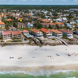 Aerial view of beachfront vacation homes with pristine white sand beach and turquoise waters stretching along the coastline.