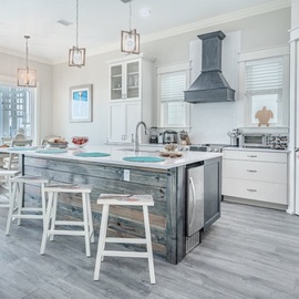 Your bright coastal kitchen invites culinary adventures with gleaming counters, modern appliances, and a rustic island perfect for morning coffee.
